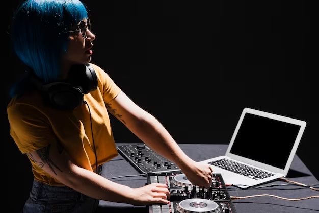 A girl with blue hair sets up music on a laptop