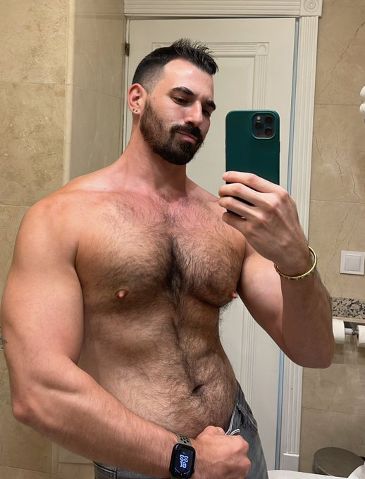 Thick Macho shirtless flexing his right arm for a mirror selfie with holding the button of his blue jeans