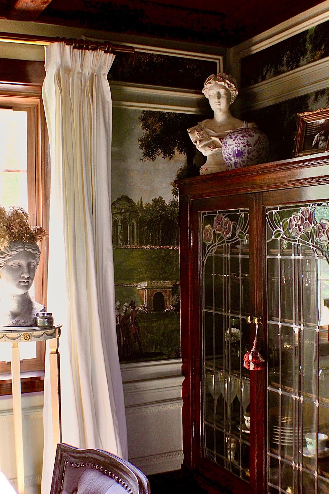 A corner in Ashley's dining room featuring a beatifully carved cabinet, couple stunning busts and wall-mounted paintings.