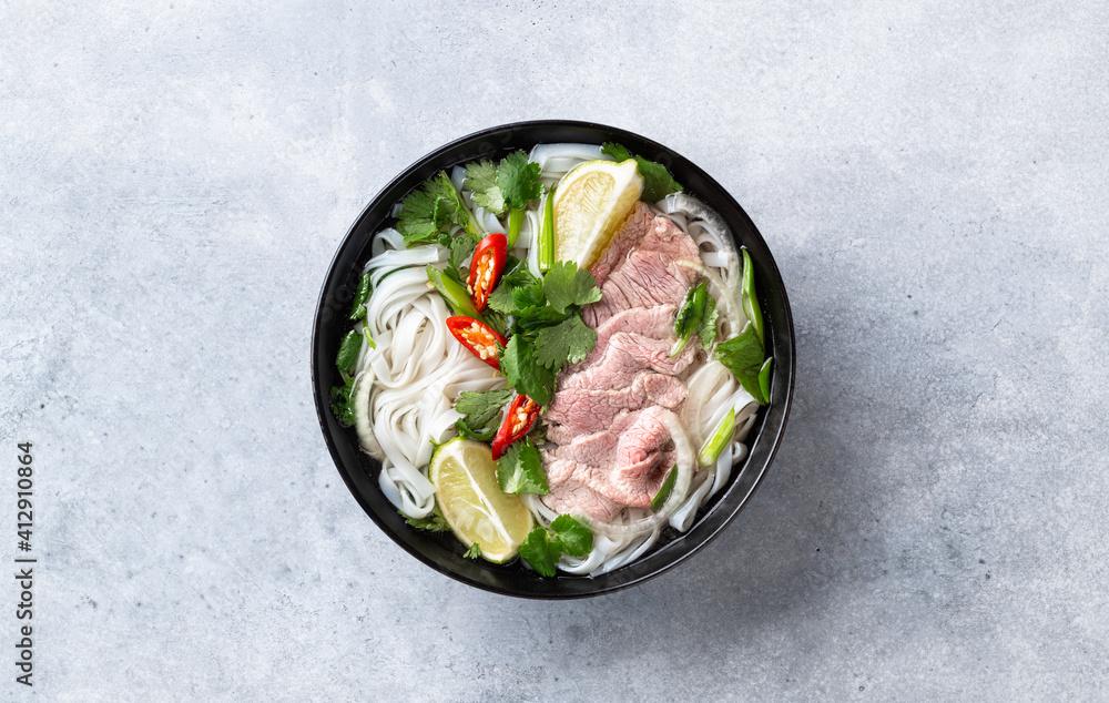 Pho Bo vietnamese soup with beef and rice noodles on a concrete background, top view