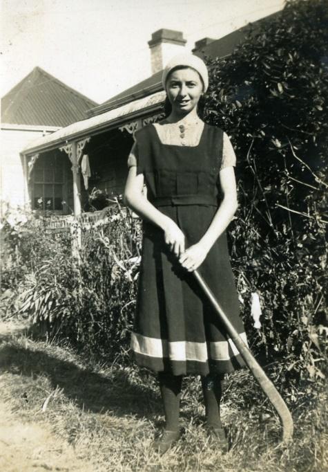 A person in a dress holding a cane in front of a house

Description automatically generated with medium confidence