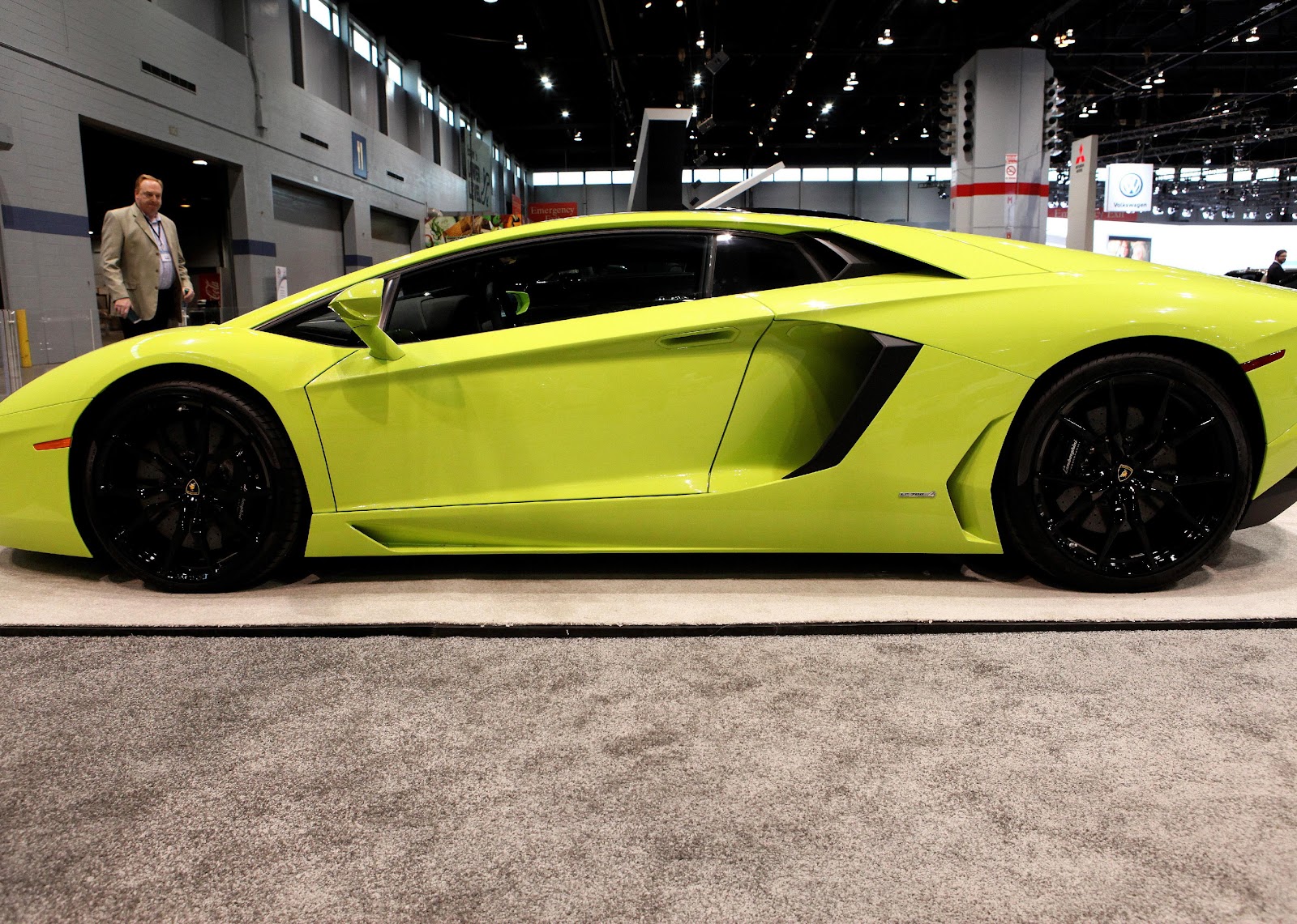 A neon yellow Lamborghini Aventador in a showroom.