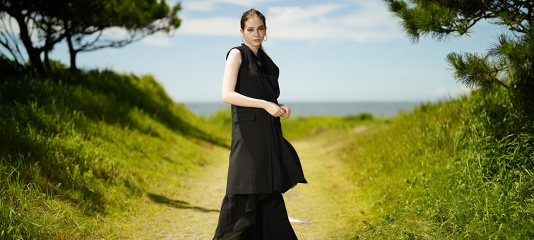 Image of a woman with beautiful bokeh, standing in a path to a beach