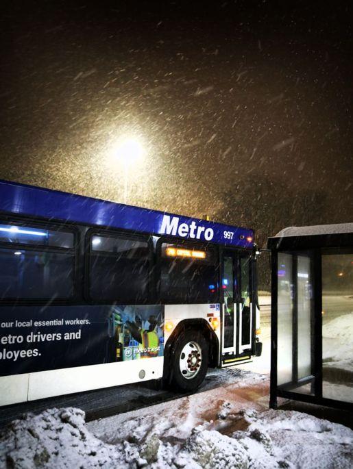 Metro Bus at a bus stop on a snowy night