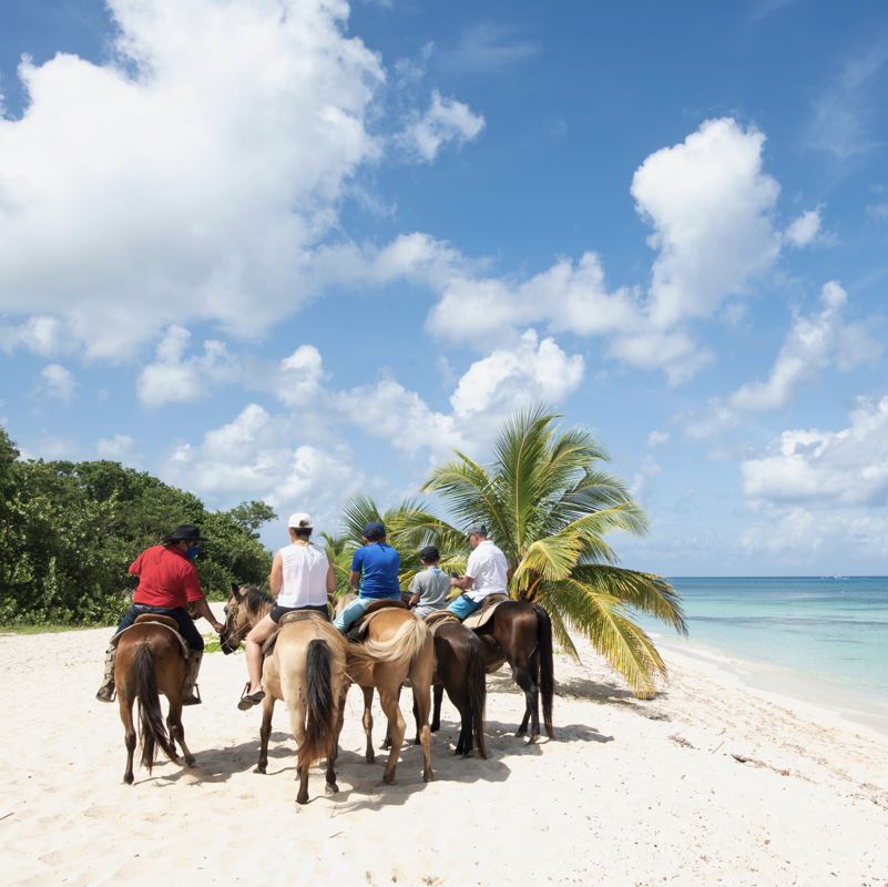 friends riding horses on a tropical beach in Cozumel
