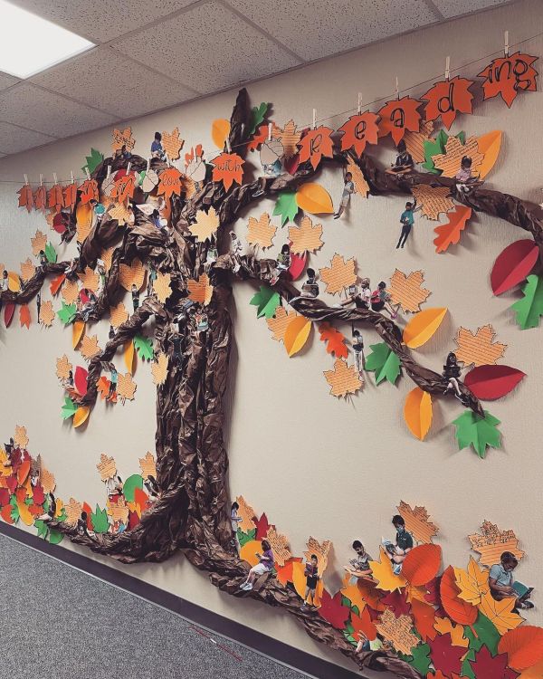 a bulletin billboard featuring a tree made of craft paper with leaves on the branches and photos of preschool children