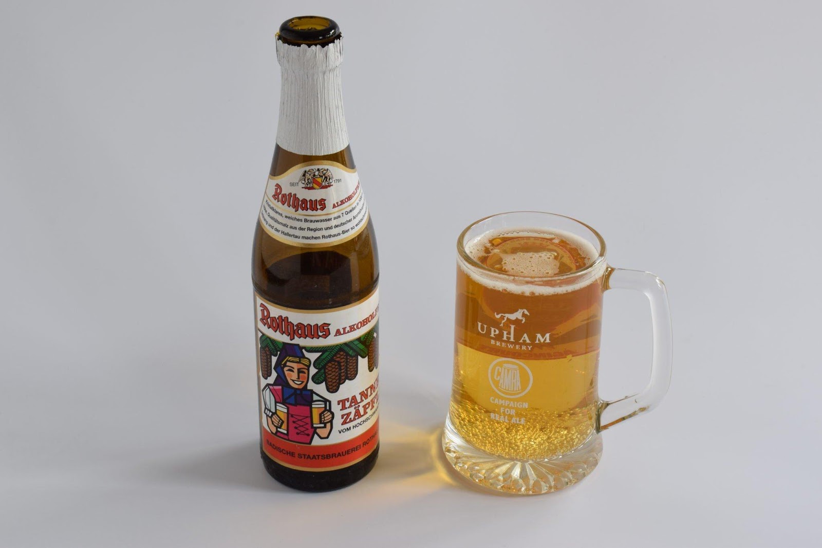 A bottle of Rothaus Tannenzäpfle beer and a full beer mug sitting on a desk
