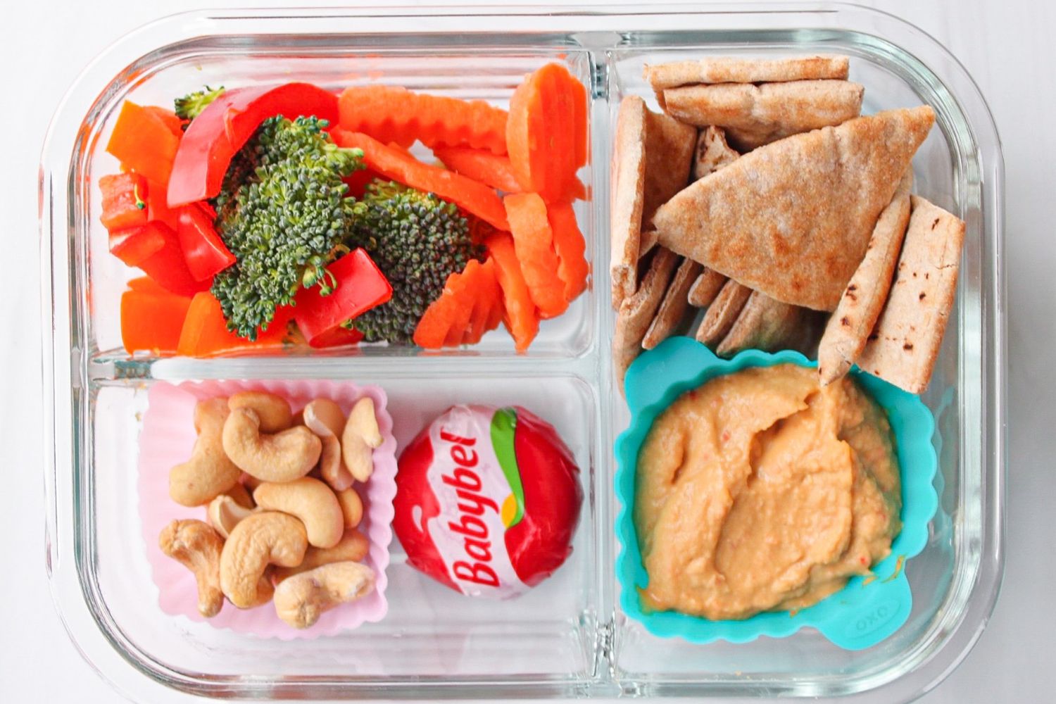 An adult lunchable with veggies, nuts, cheese, hummus and pita bread.