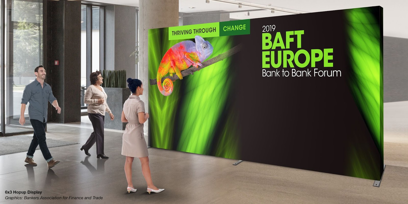 A Large backdrop shows the BAFT Europe 2019 artwork of a chameleon scaling a bright green leaf against a black background