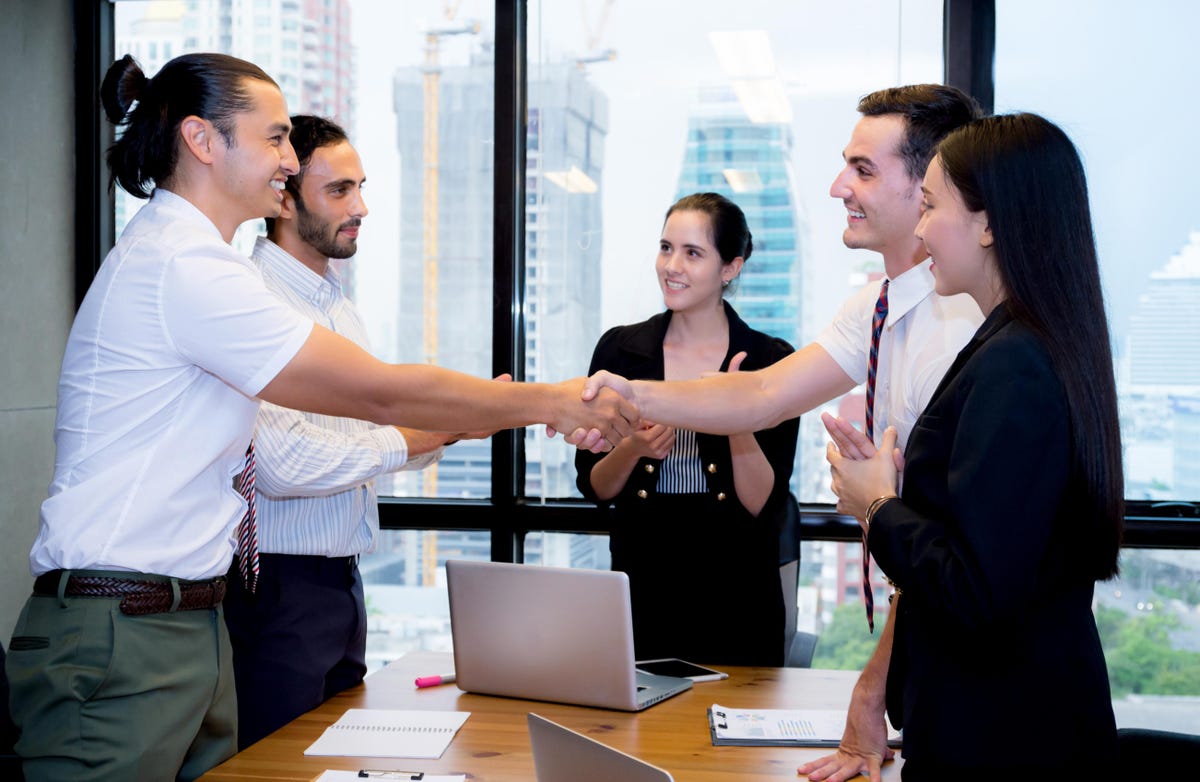 Image shows employees agreeing and shaking hands in a meeting