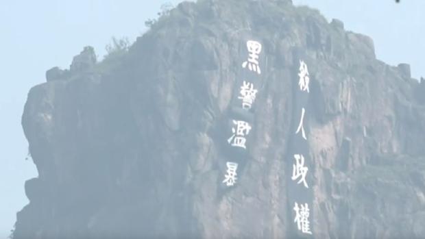 2019年8月24日,狮子山山头位置被挂上两条大型直幡,写著「黑警滥暴」及「杀人政权」。(香港突发事故报料区 facebook截图)