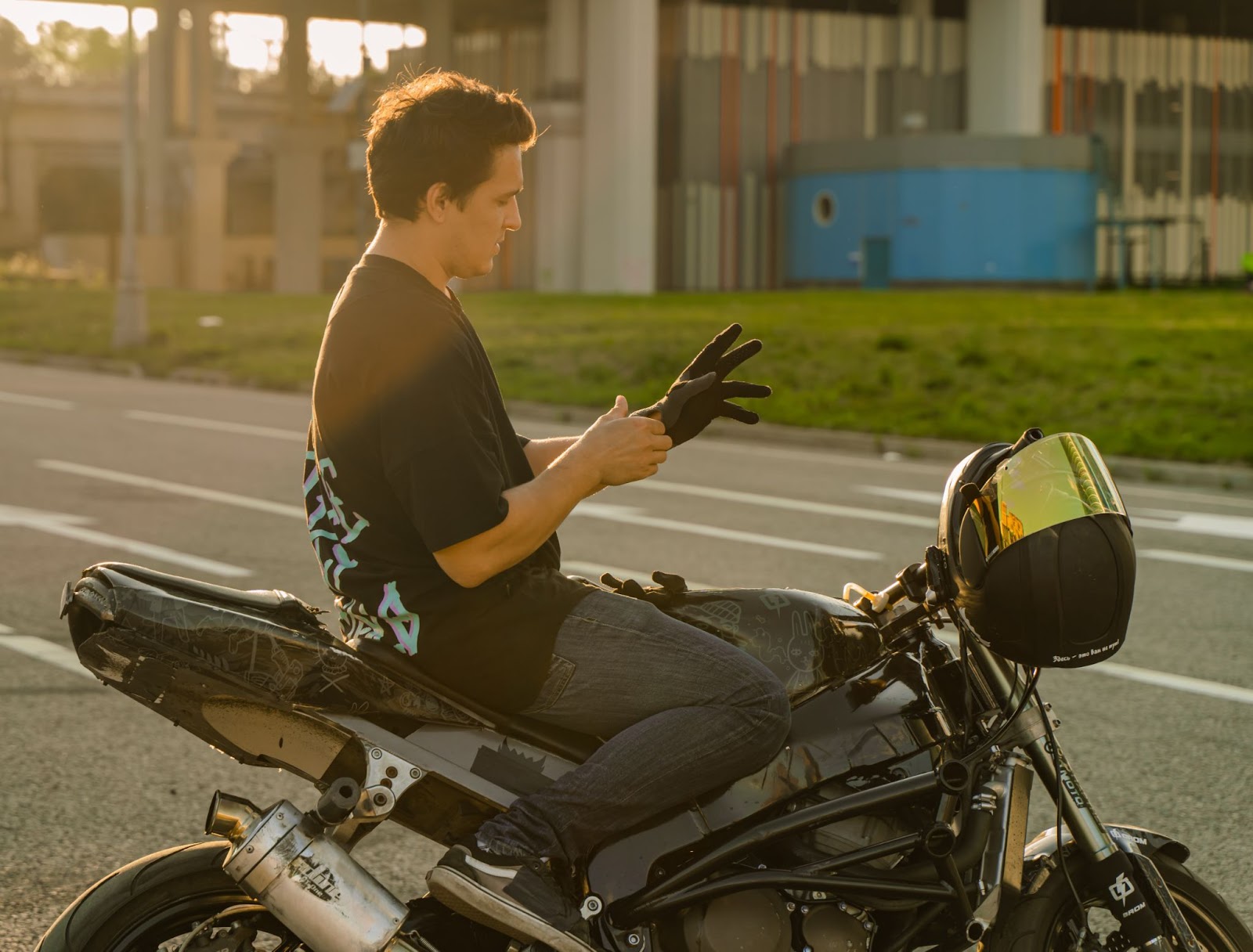 Homem sentado na moto colocando luva
