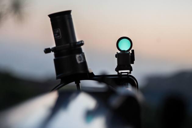 A close-up of the Celestron's finder scope, with a pale sky out of focus in the background.