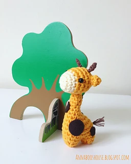 tiny giraffe amigurumi in front of toy tree