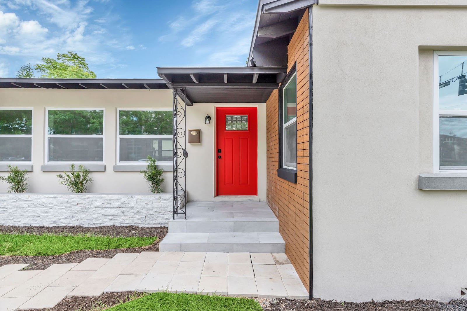 The front of a home with steps leading up to a bright red front door.