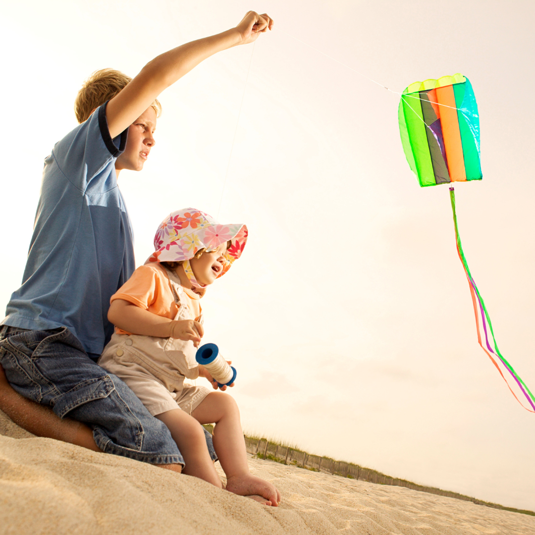 Two children flying a kite on the beach outside