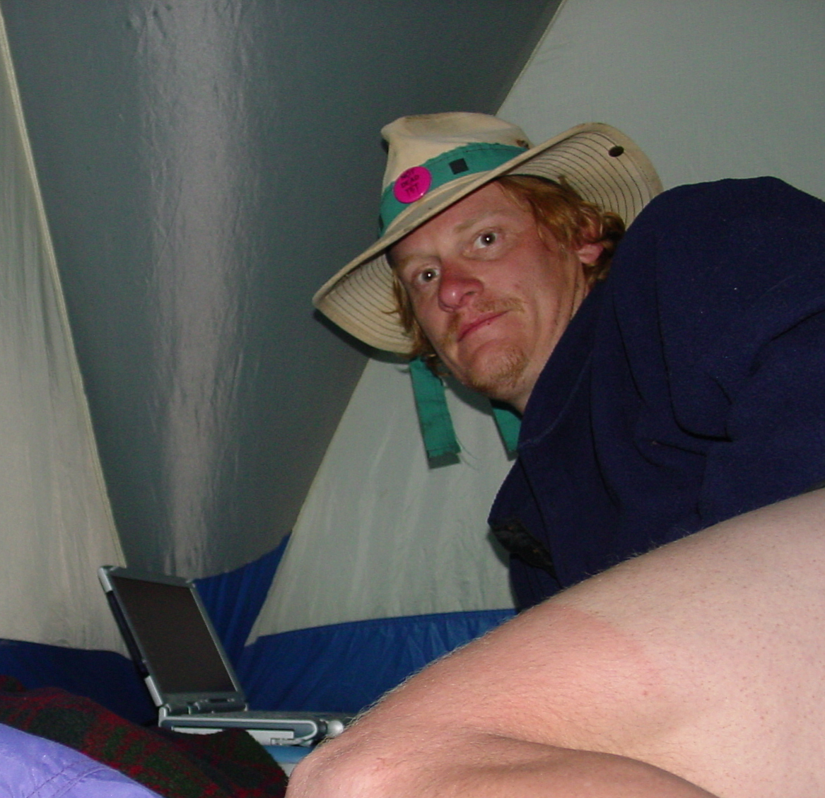 Man wearing a large brim hat in a cramped tent