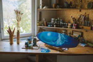 The process of painting an ocean on a surfboard, an example of a coastal home décor idea.