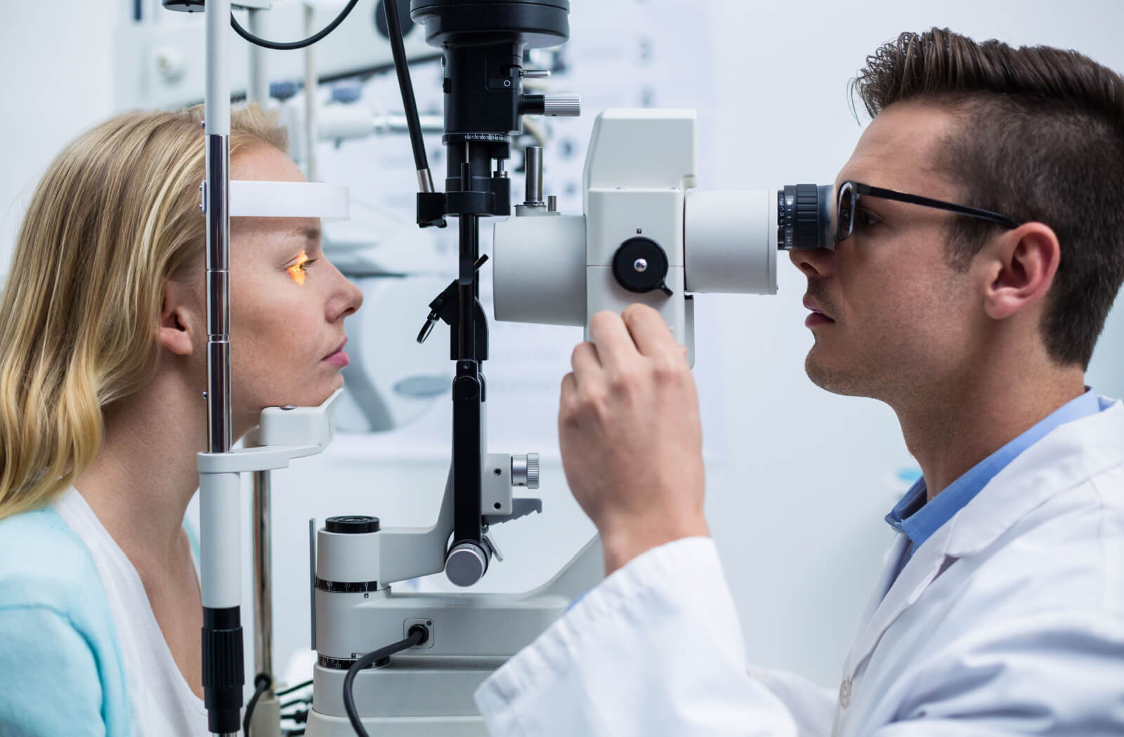 A female patient receiving an eye examination from a male optometrist