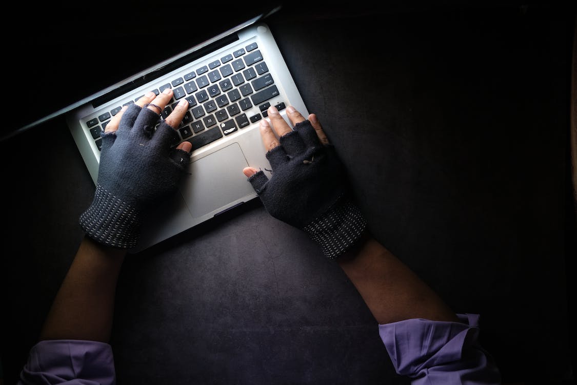 Free A Person Typing on Laptop while Wearing a Fingerless Gloves Stock Photo
