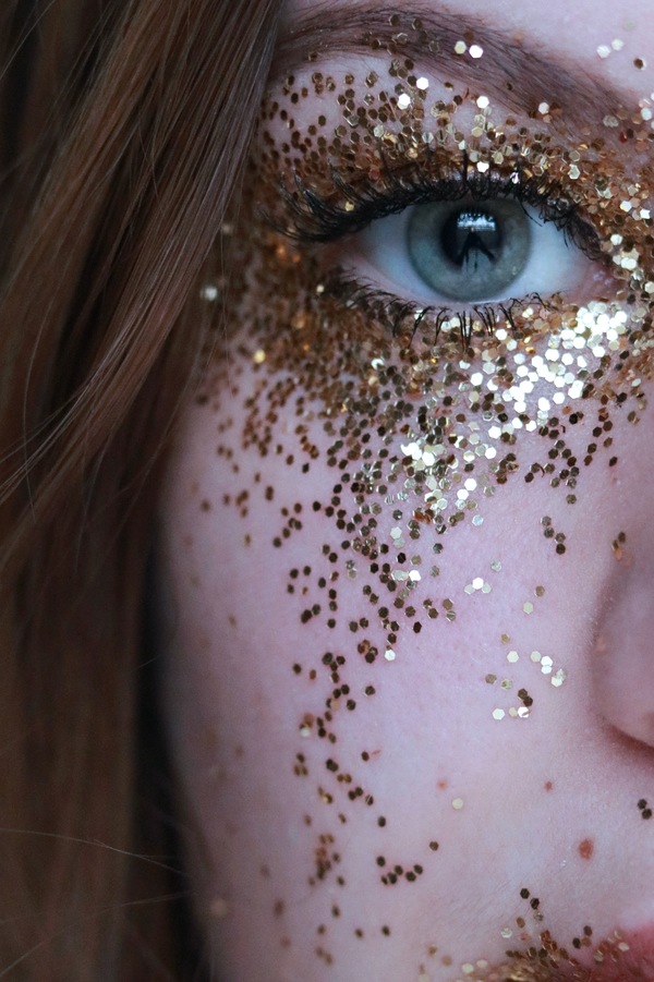 foto do olho verde de uma mulher com glitter em volta do olho 