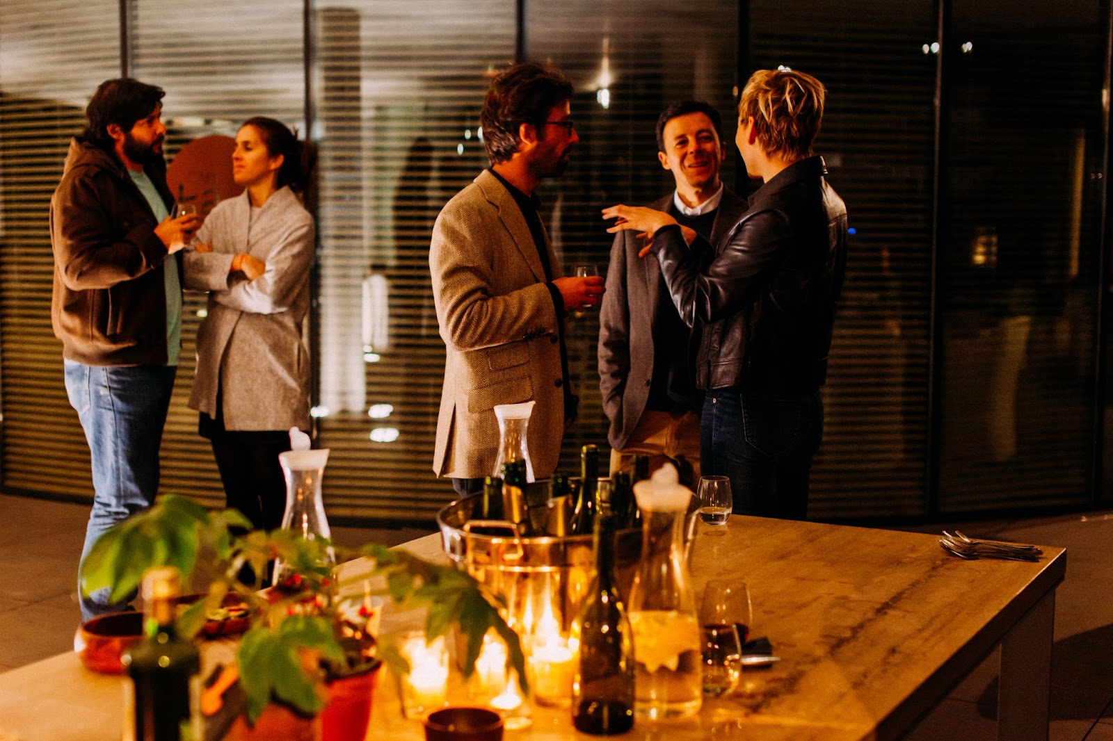 People stand and chat over drinks at an office holiday party