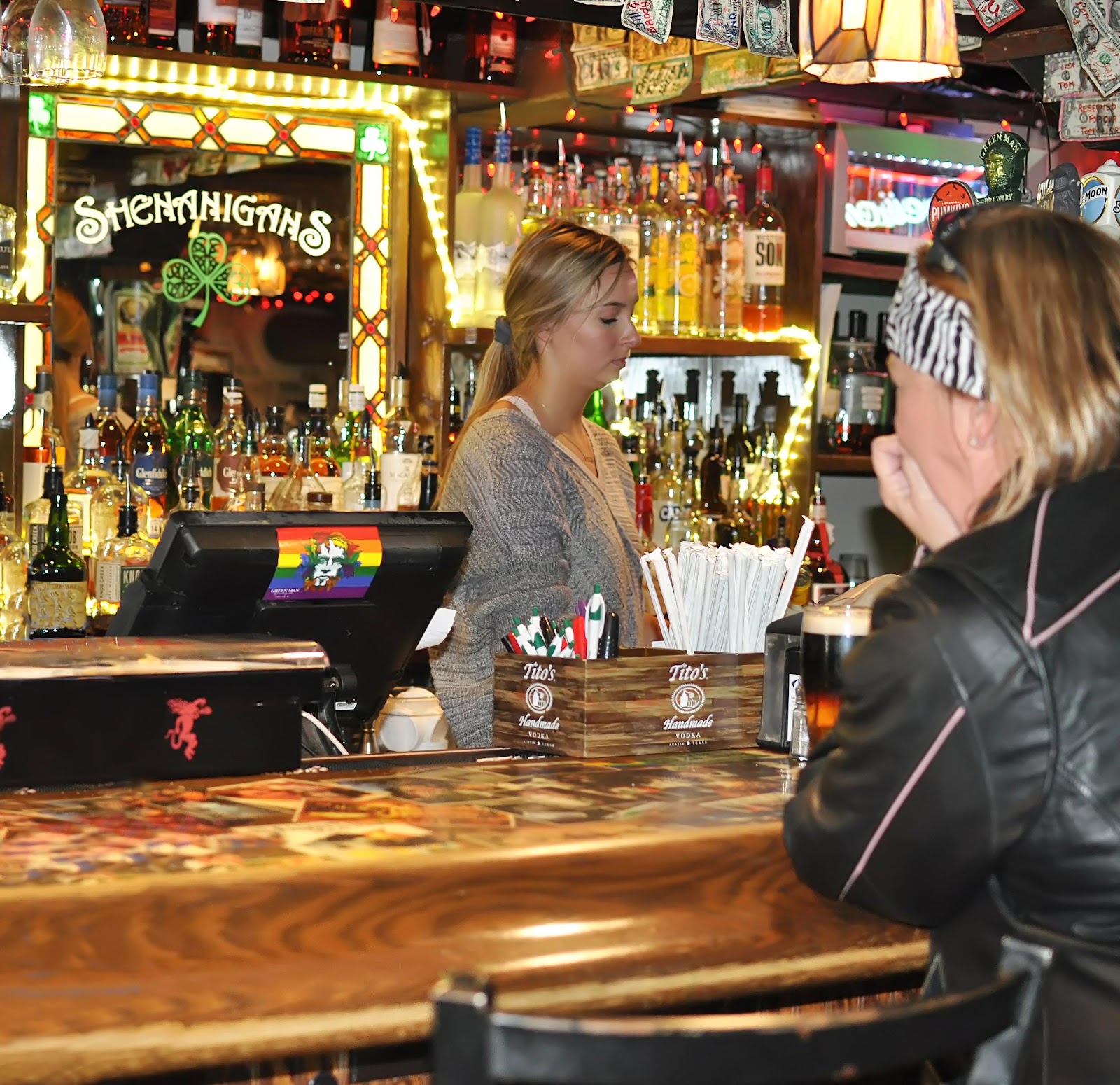 A bartender making drinks and a woman seated at the bar.