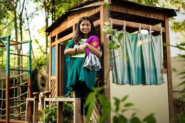Fotografía de la joven activista del cambio climático en Pakistán, Emaan Khan, en la puerta de una pequeña casa de juegos de madera.