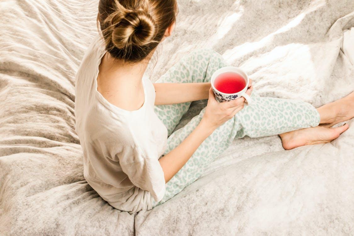 Free Aerial View Photography of Woman Sitting on Blanket While Holding Mug Filled With Pink Liquid Looking Sideward Stock Photo