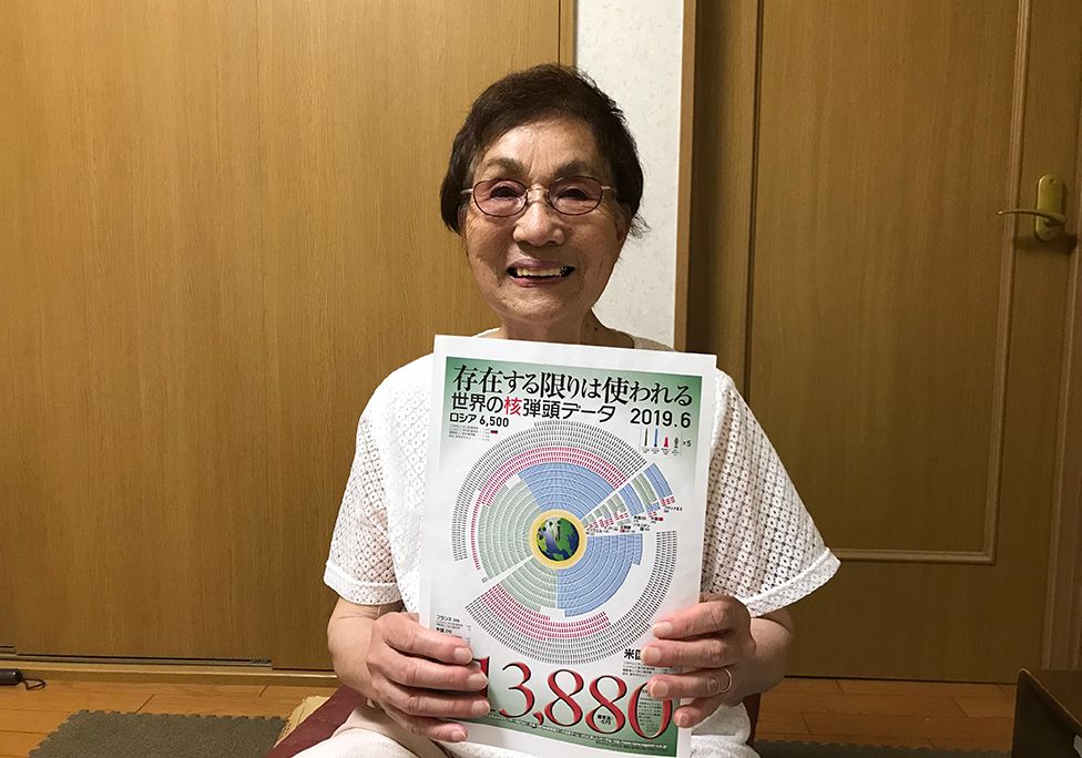 An elderly lady holds up a diagram to the camera