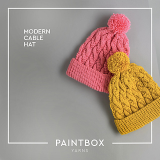 pink and mustard colored cable knit hats on gray background