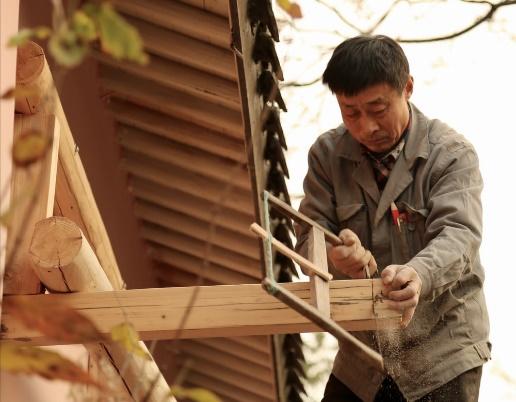 man in gray jacket holding brown wooden frame