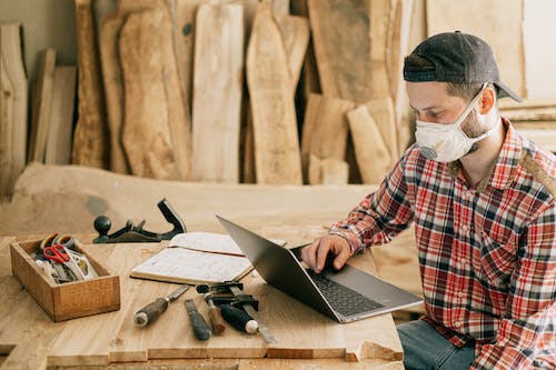 Free Man Using a Laptop at a Wood Workshop Stock Photo