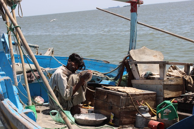 The fishermen perform multiple tasks on the boat. This man makes fresh rotis (flat bread) from whole-meal flour, which the men eat with the fish they catch.  Credit: Zofeen Ebrahim/IPS