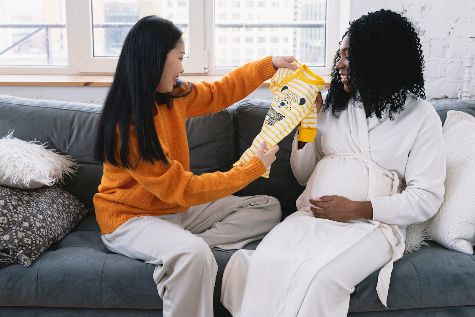 Pregnant woman receiving baby cloth gift.