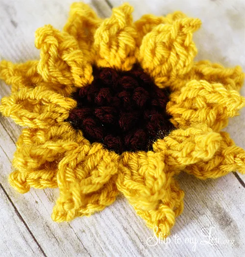 crochet sunflower on white wooden background