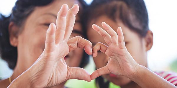 Lady and young boy forming a heart with their hands together
