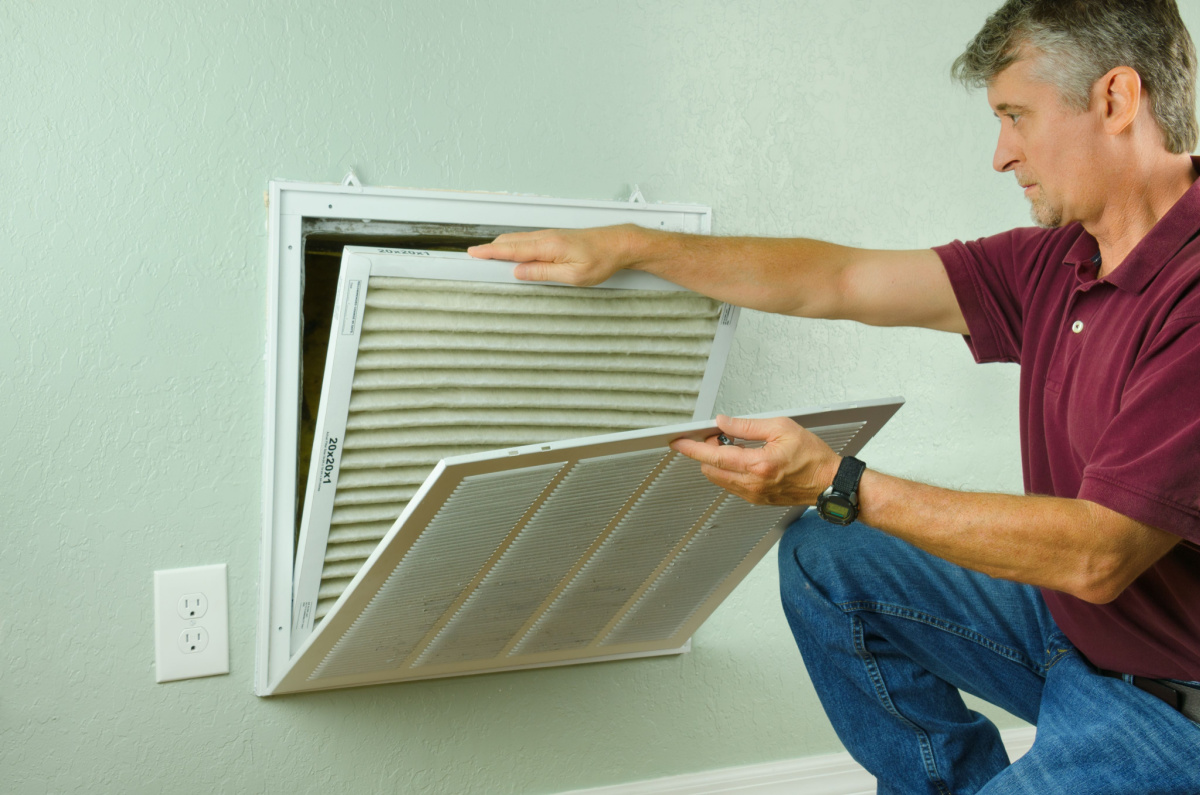A man replacing an HVAC system air filter.