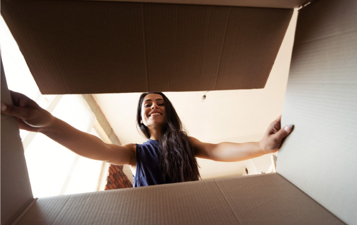 View from inside a moving box as a smiling woman opens it