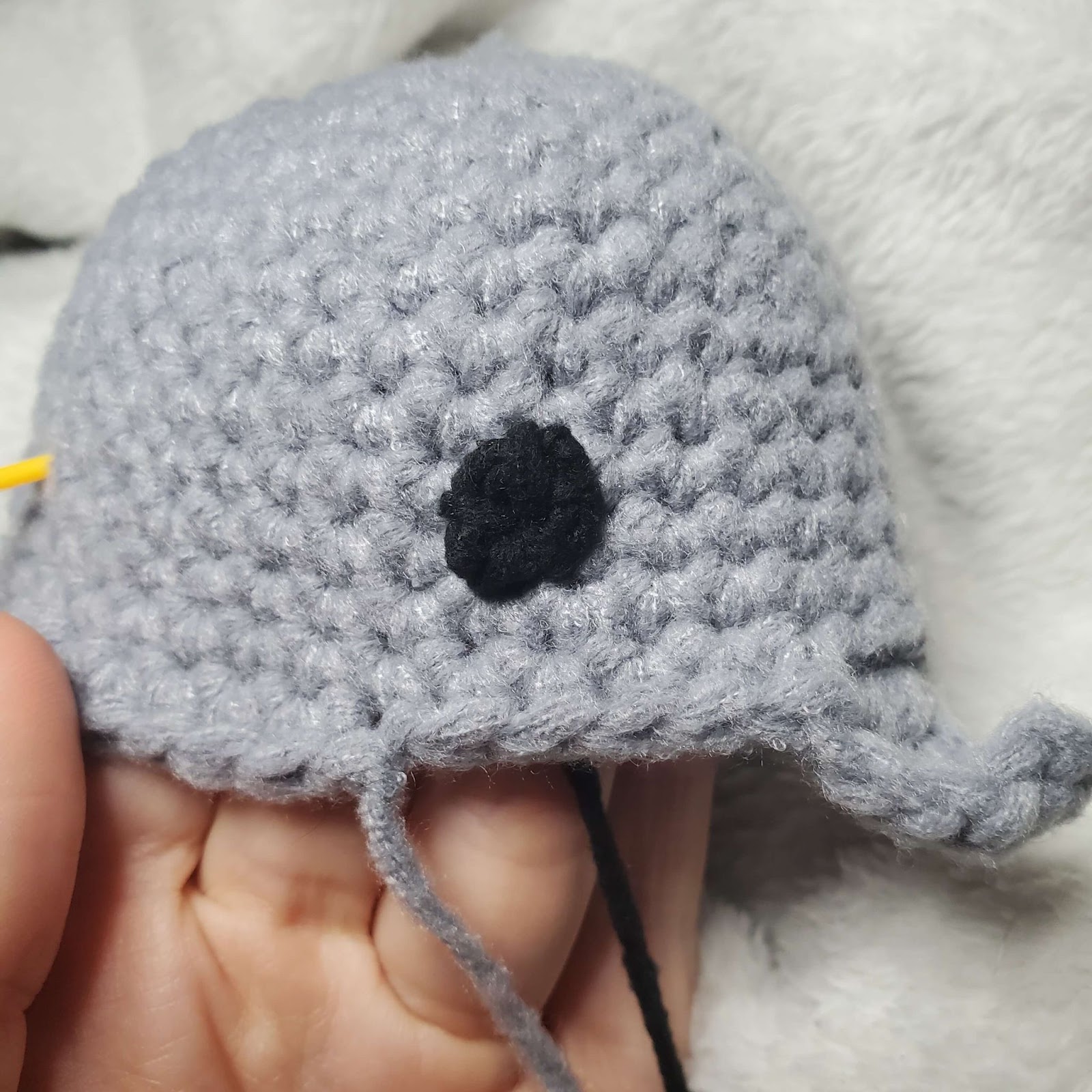 Image shows the completed embroidery of the crochet shark lovey eye.