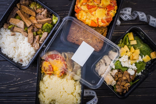 Packed of healthy meals per container with tape measure served on a wooden table