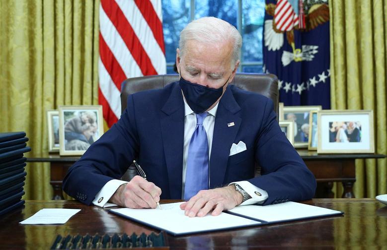 President Joe Biden signs executive orders in the Oval Office of the White House. REUTERS/Tom Brenner