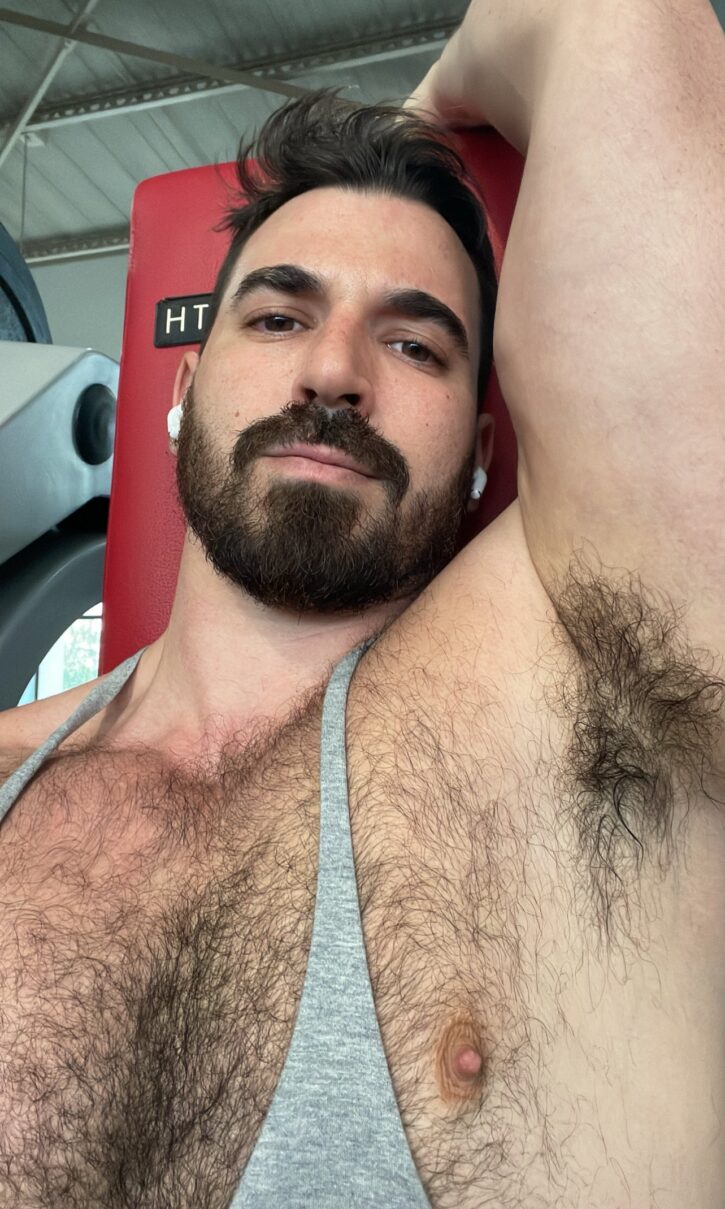 Thick Macho smiling showing off his sweaty arm pit and thick hairy chest in a grey tanktop that doesn't cover his nipples