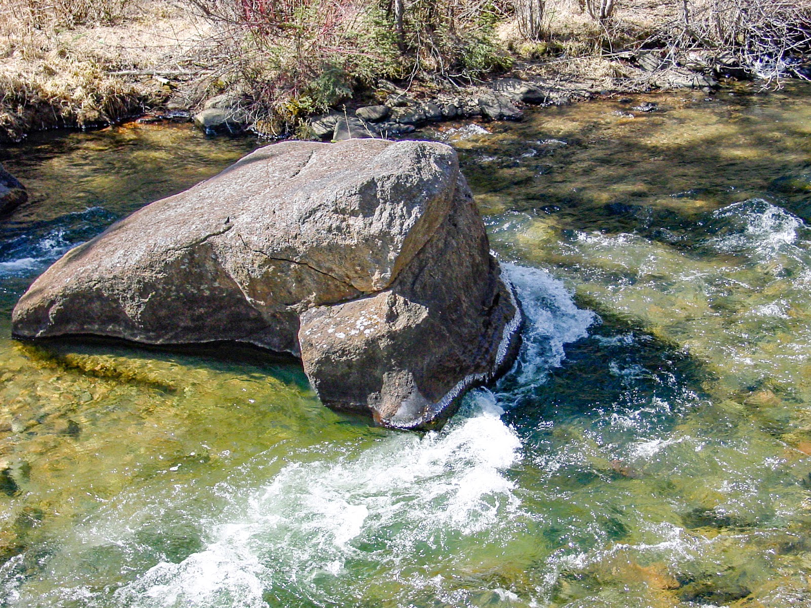 A large rock has water running around both sides. 