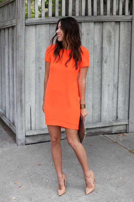 Woman in orange frock posing and smiling