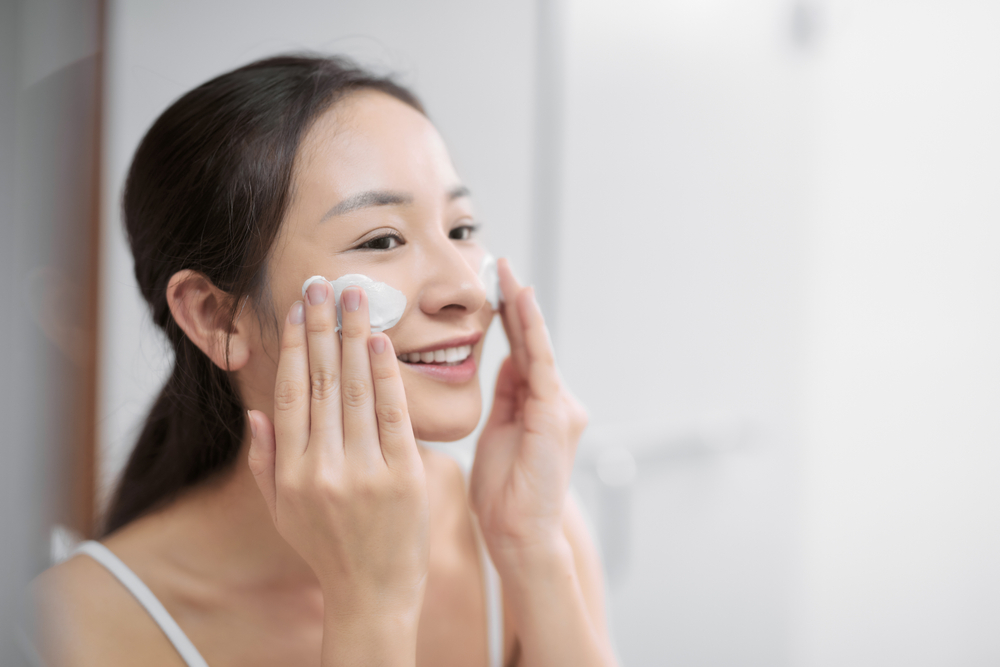 Young woman using a facial cleanser.