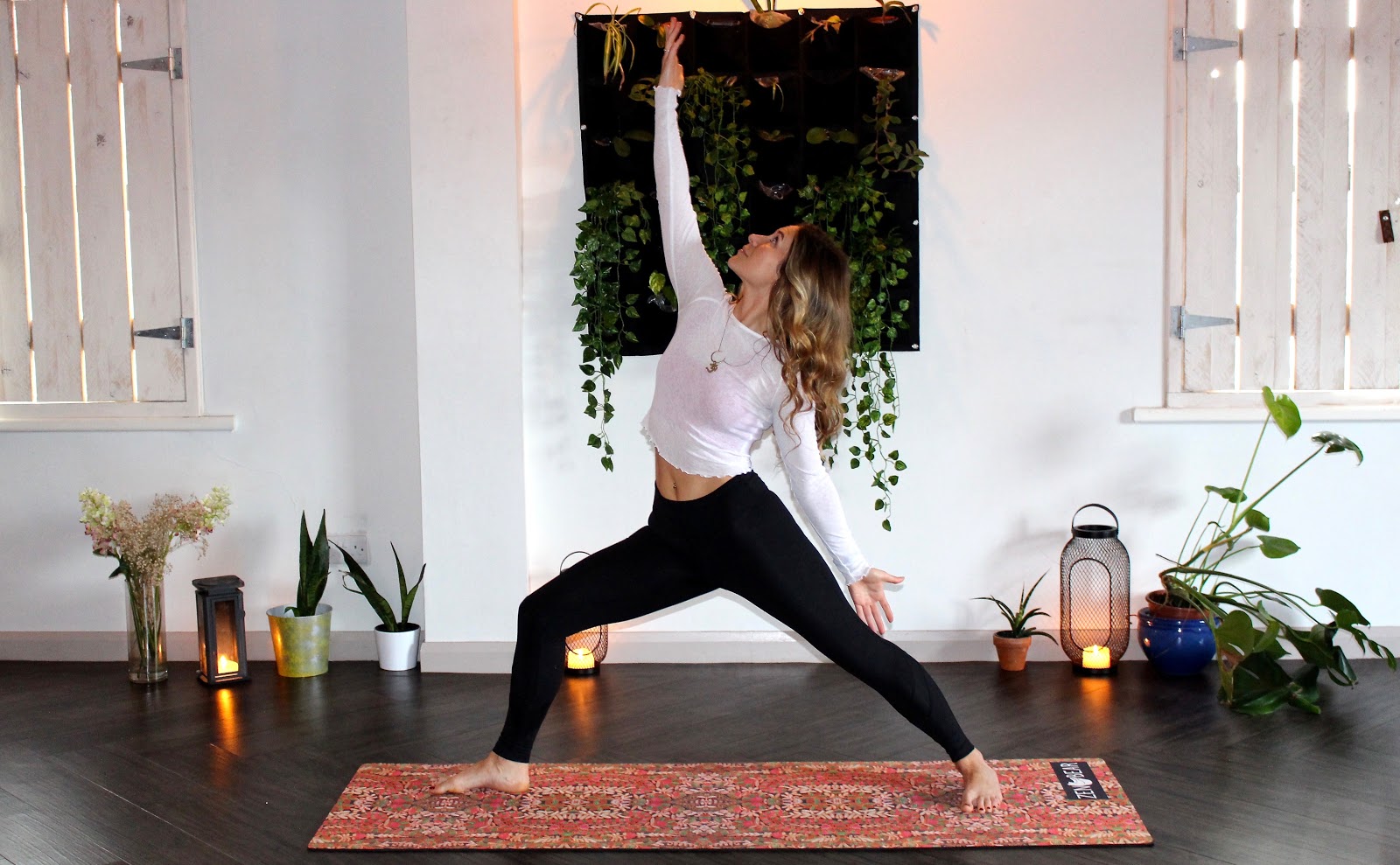 Foto de uma mulher loira fazendo yoga sobre um tapete estampado.