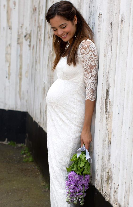 A bride wearing a lace wedding gown and holding green and lilac flowers