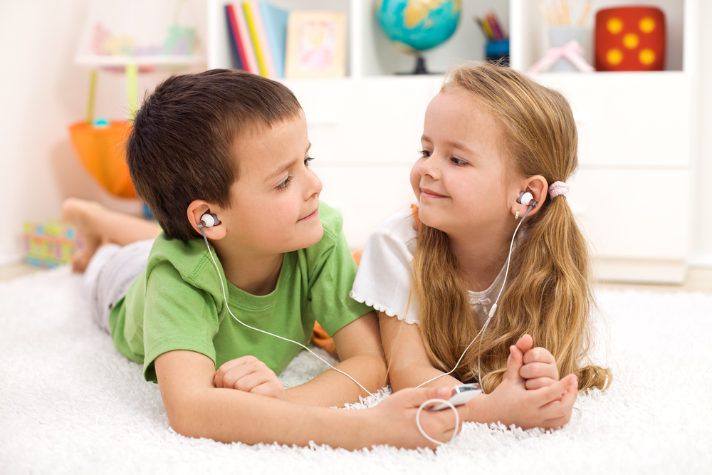 two kids sharing headphones to listen to music