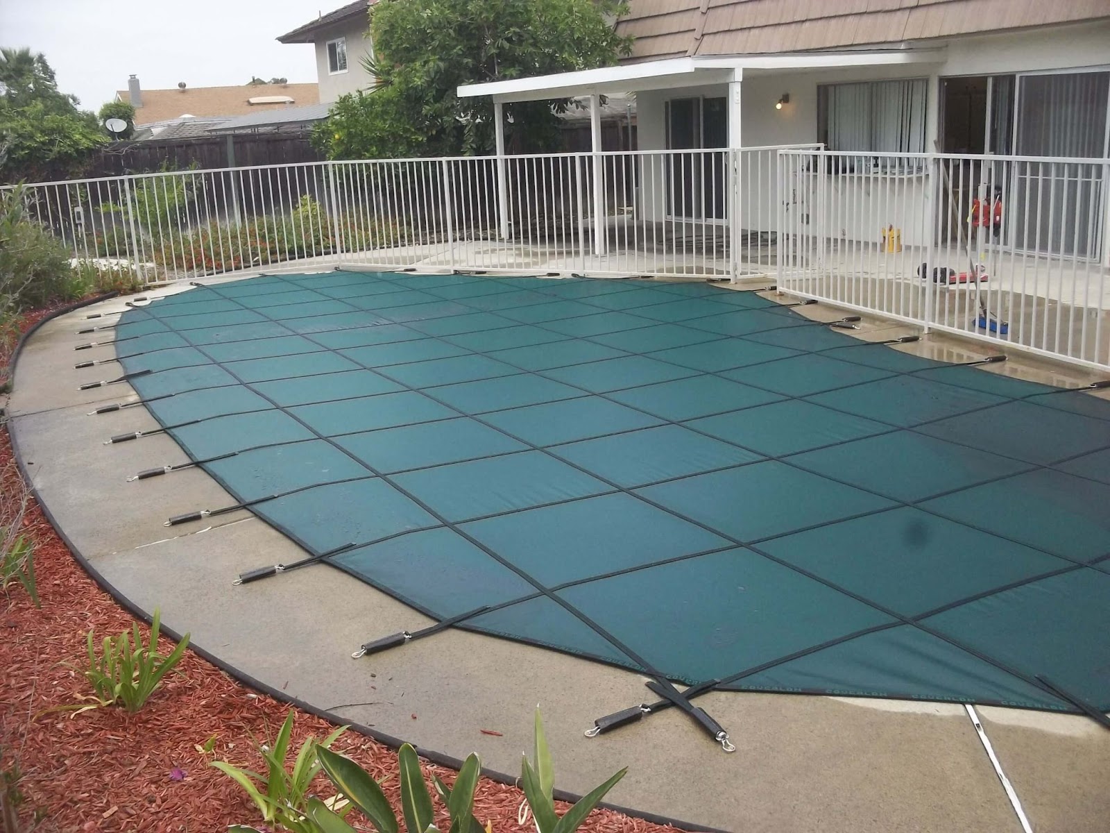 Green winter pool safety cover installed on an irregular pool